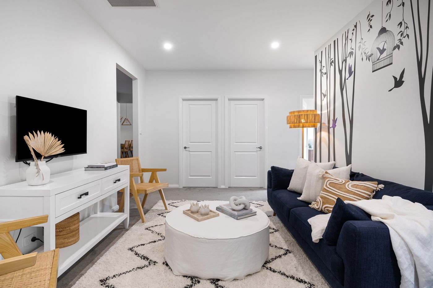 Lichte woonkamer met witte muren, houten vloer en een blauwe bank